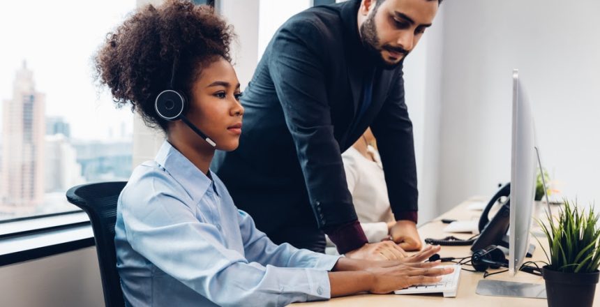 Call center business woman talking on headset. Call center worker accompanied by her team. Customer service executive working at office.