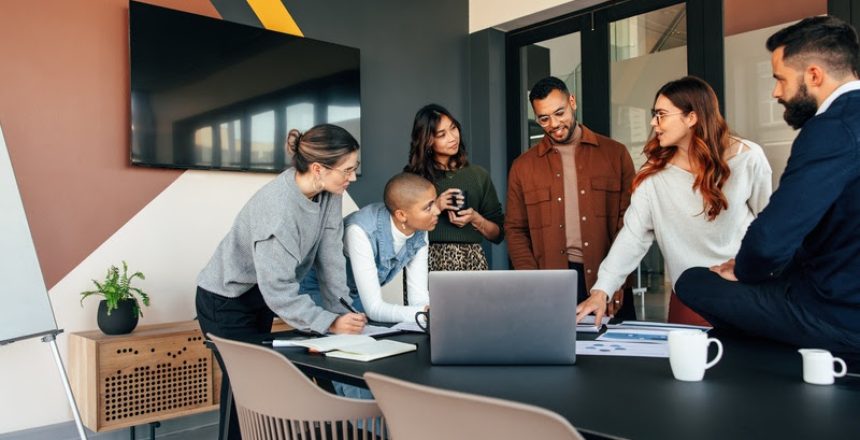 Diverse businesspeople discussing some reports in a boardroom. Group of multicultural businesspeople standing around a table in a modern office. Young entrepreneurs collaborating on a project.